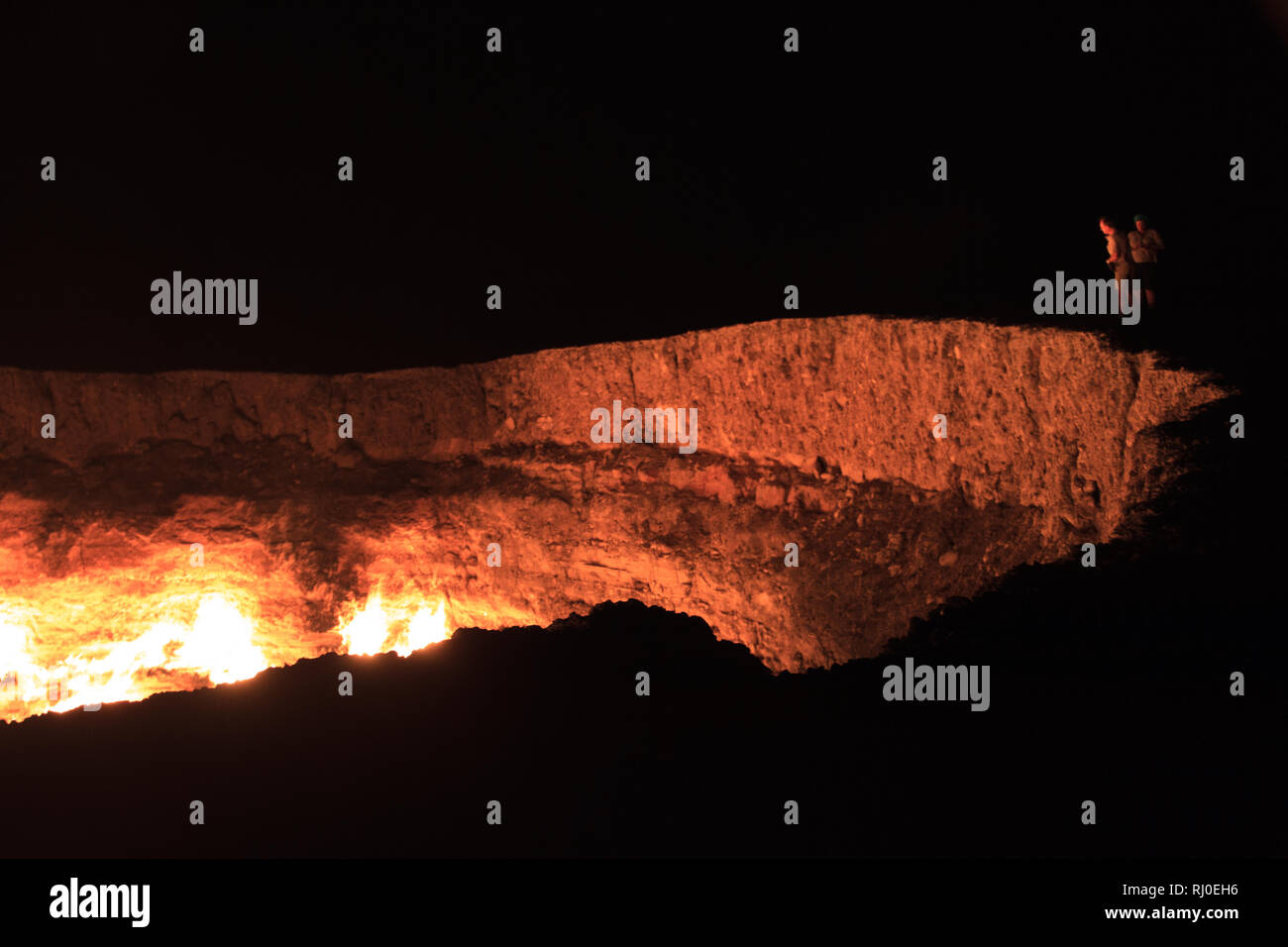 People looking down into The Darvasa Crater, also known as the Doorway to Hell, the flaming gas crater in Darvaza (Darvasa), Turkmenistan Stock Photo