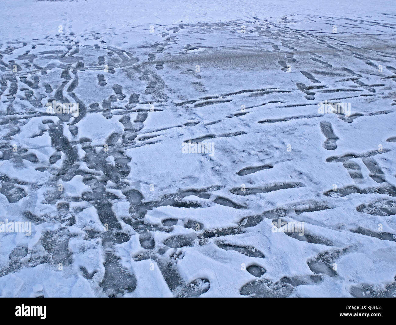 Frozen surface of lake in winter with many human footprints Stock Photo