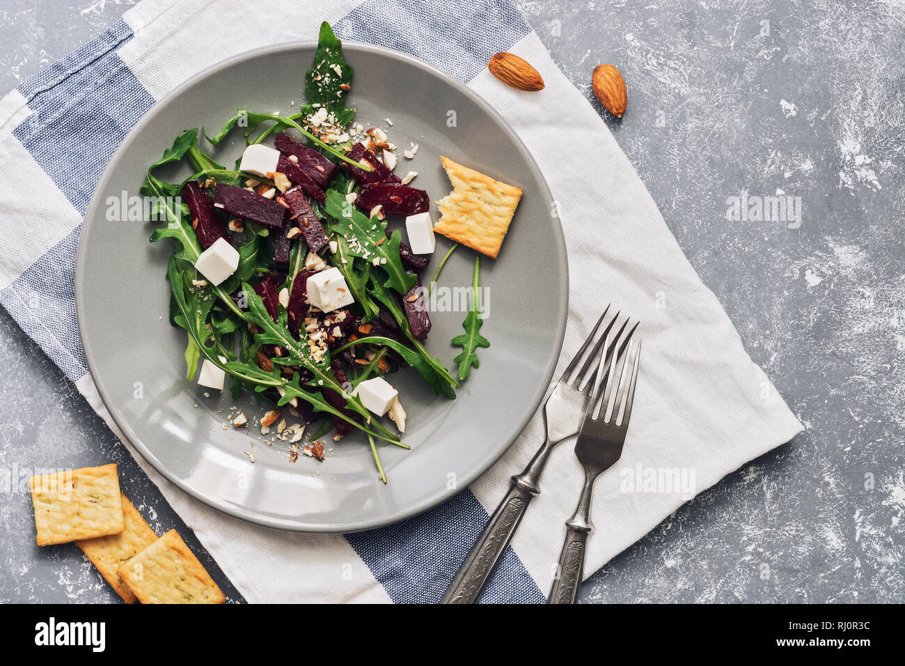 Vegan diet salad with beetroot, arugula, feta cheese with crackers, gray background. The concept of healthy eating. Top view, flat lay Stock Photo