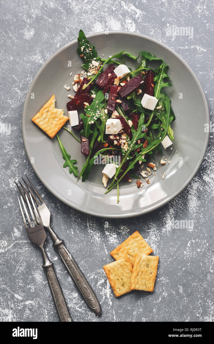 Vegetarian salad with arugula, beetroot, and feta cheese on a gray background. Healthy vegan food. Top view, toned Stock Photo