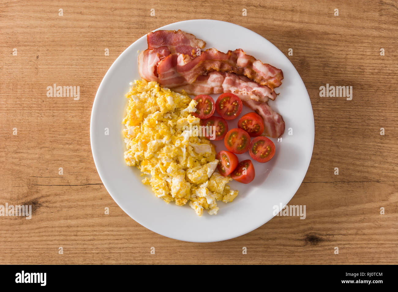 Breakfast With Scrambled Eggs Bacon And Tomatoes On Wooden Table Top View Stock Photo Alamy