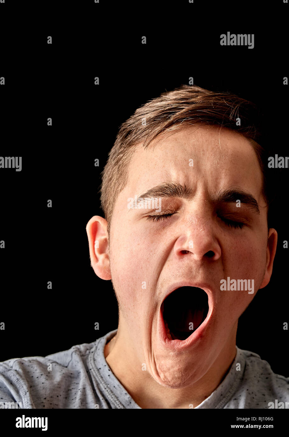 A bored male teenager yawns with mouth wide open Stock Photo