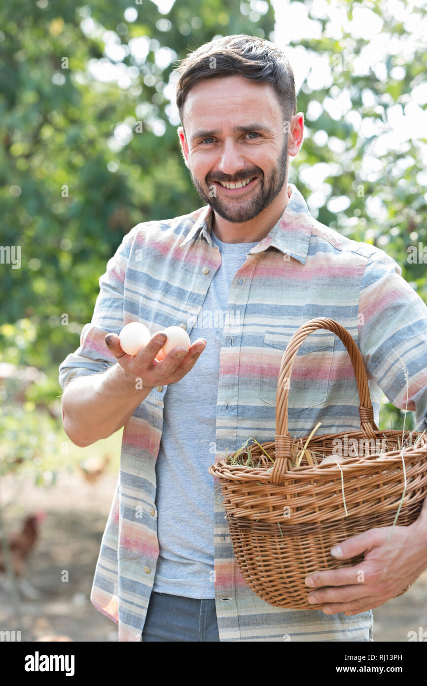 Portrait of smiling farmer holding eggs in basket at farm Stock Photo