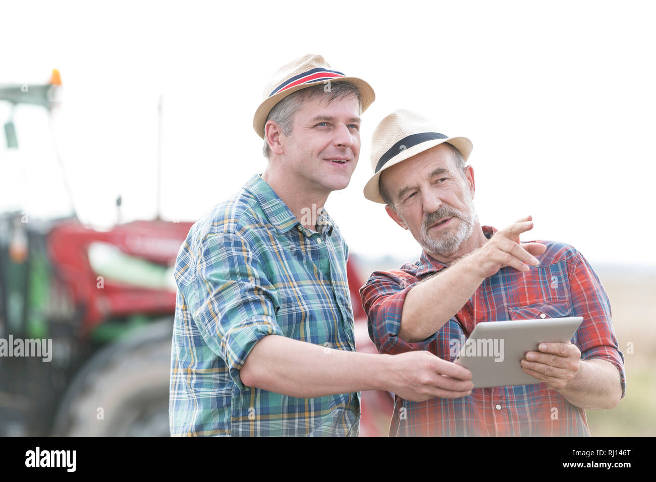 Confident farmers with digital tablet discussing at farm Stock Photo