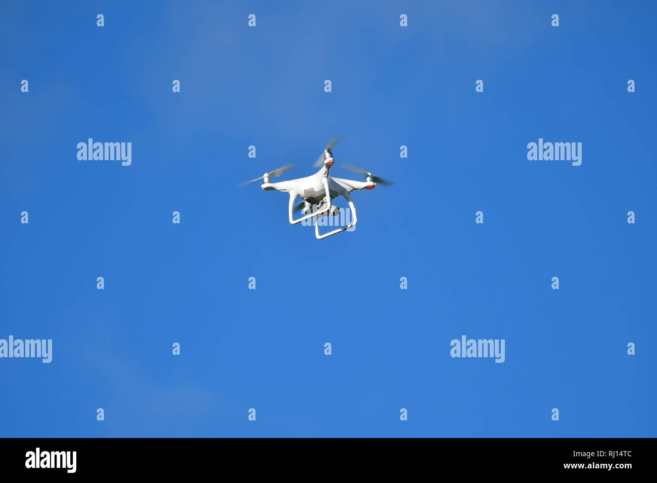 A Drone against a plain blue sky Stock Photo