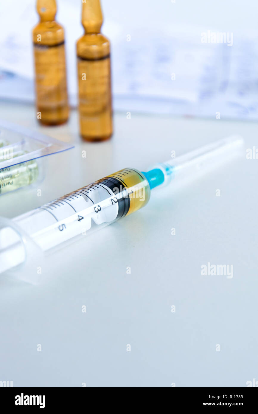 Medical syringe with injection solution, medicine pills and capsules on ...