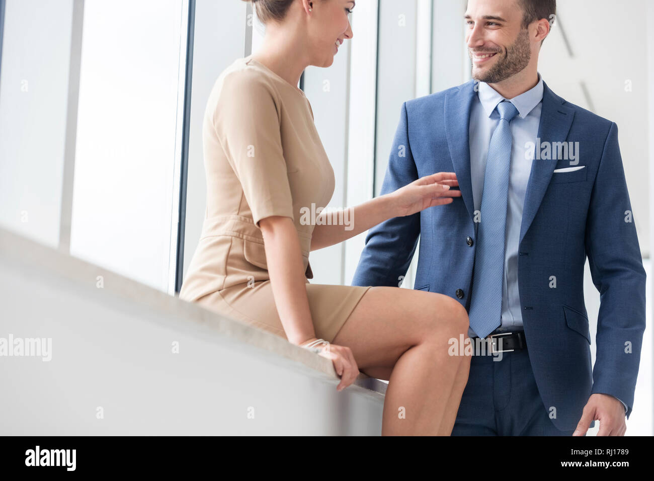 Smiling young business colleagues talking by window at new office Stock Photo