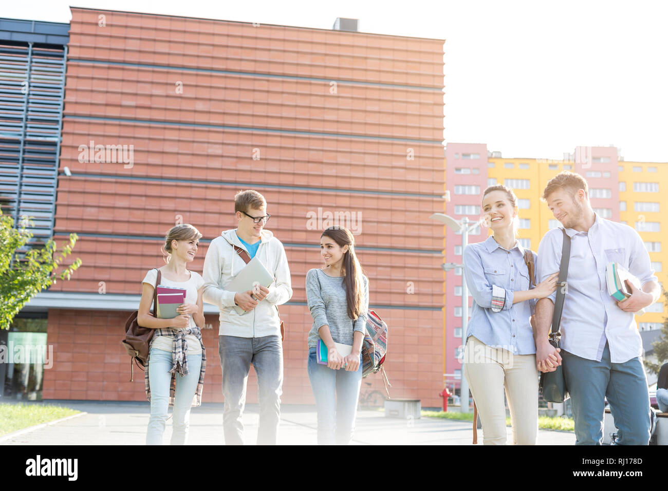 Smiling couple walking with friends in college campus Stock Photo