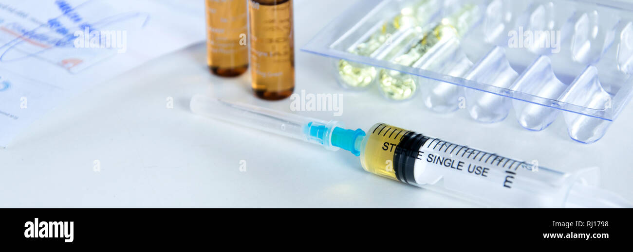 Medical syringe with injection solution, medicine pills and capsules on ...