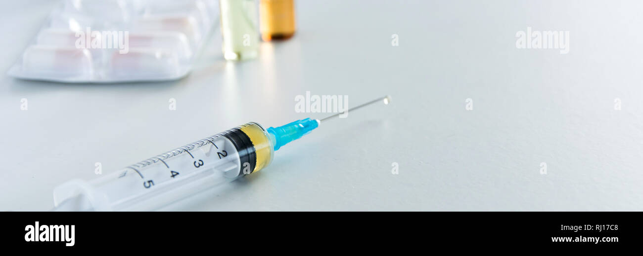 Medical syringe with injection solution, medicine pills and capsules on ...