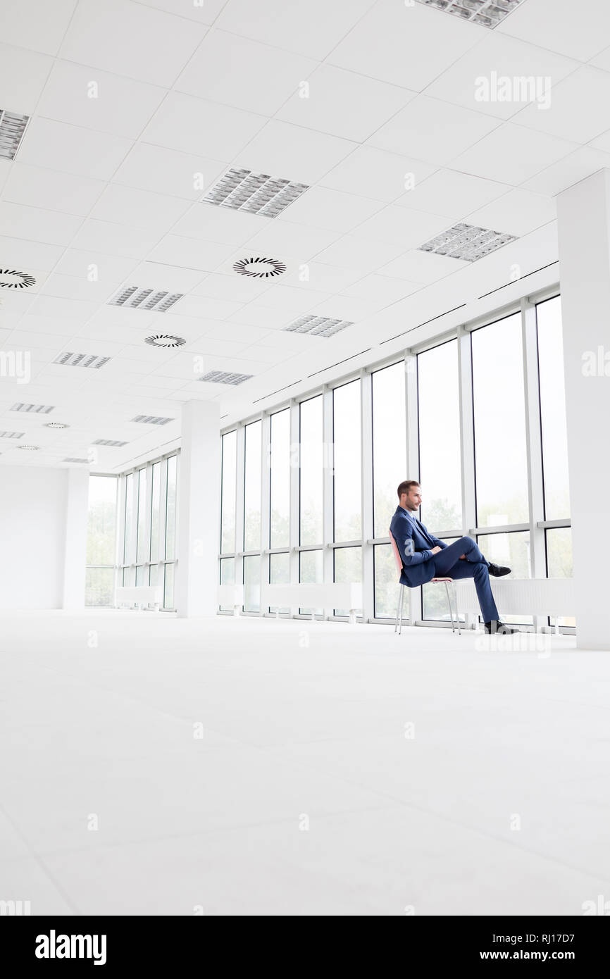 Full length side view of businessman sitting on chair at new empty office Stock Photo