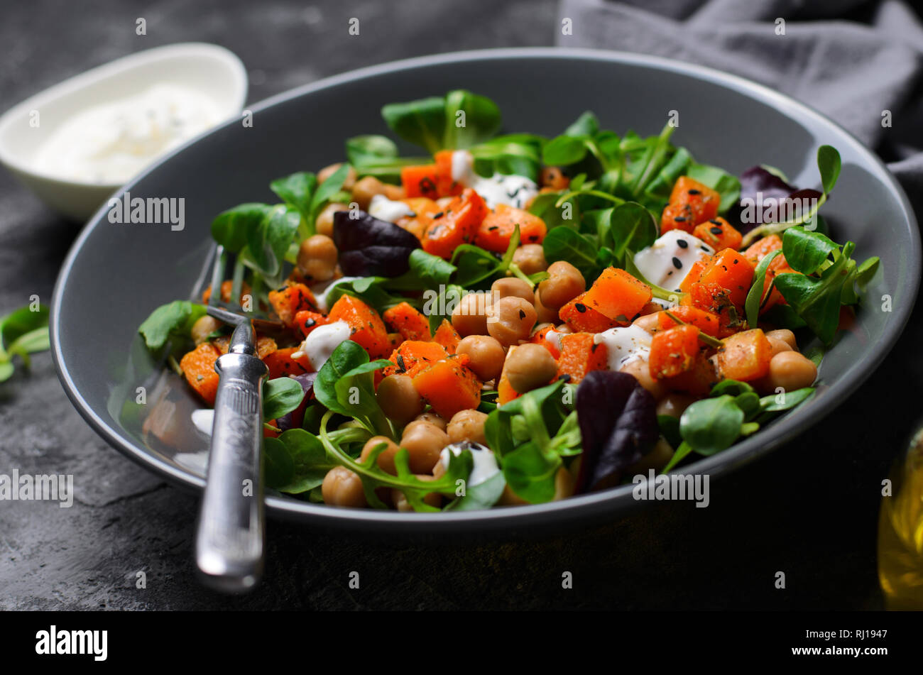 Healthy Vegetarian Salad, Roasted Pumpkin and Chickpea Salad in a Bowl on Grey Background Stock Photo