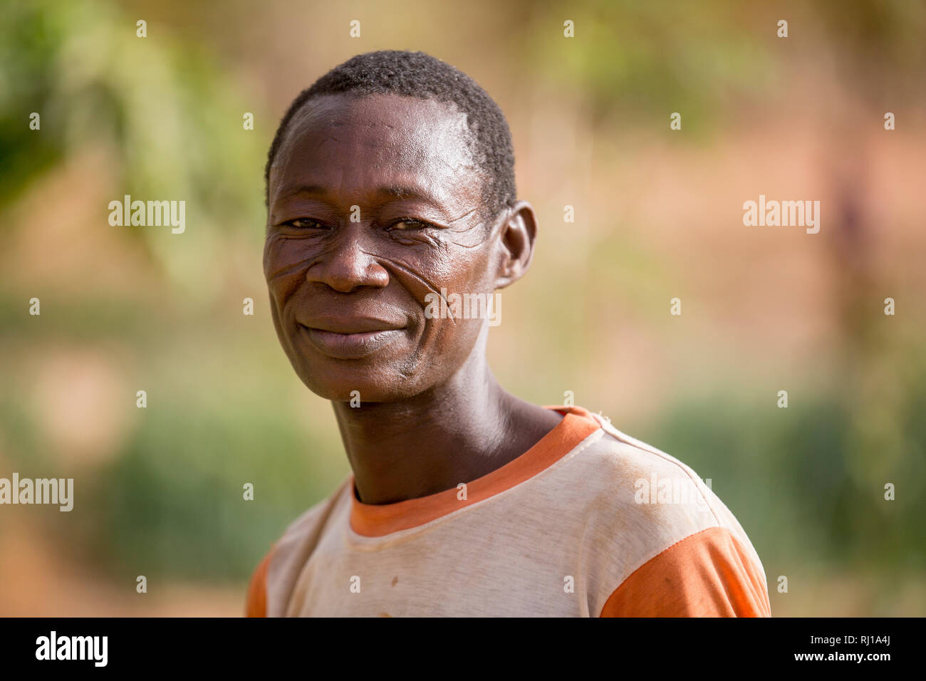 Samba village, Yako Province, Burkina Faso: Portait of Denis Zoundi, 45,with tribal scars, while watering crops on his market garden. Stock Photo