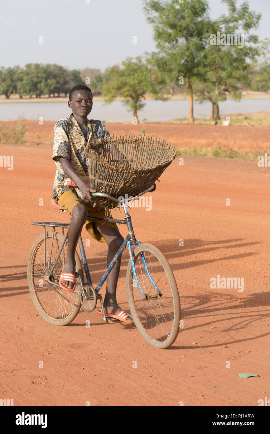 Samba village, Yako Province, Burkina Faso: A young fisherman on his way with his fishing baket to catch fish in the lake on one of the days when fishing is allowed. Stock Photo