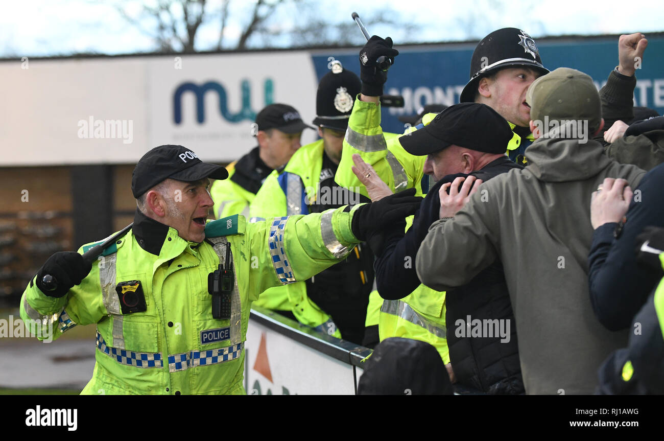 British police officer with batons drawn policing football match during crowd disturbance UK Stock Photo