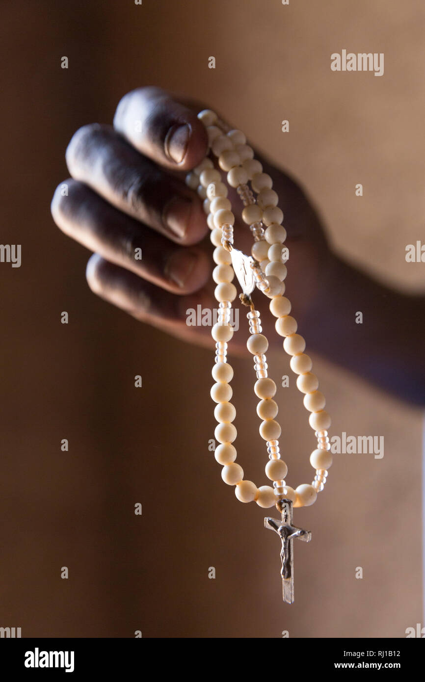 Samba village, Yako Province, Burkina Faso: Abzetta Sondo, 19, holds a rosary. Her child is suffering from acute malnutrition. Stock Photo
