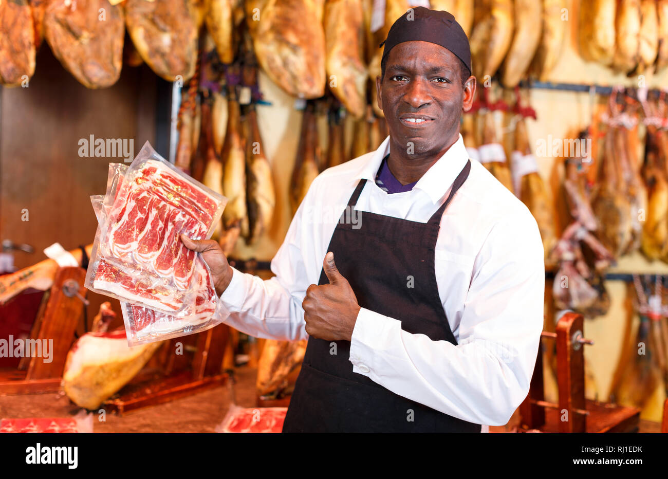 Successful owner of butcher shop selling traditional spanish jamon