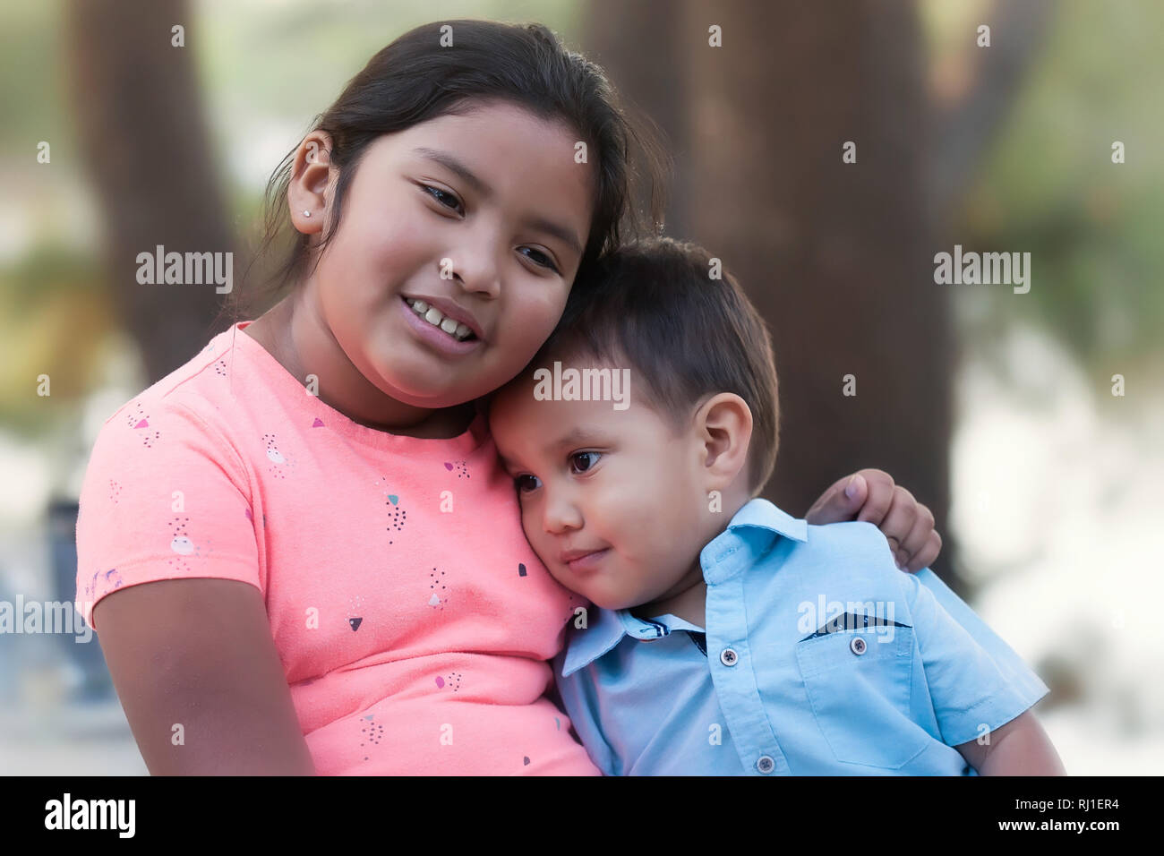 A young girl hugging a little boy and trying to encourage him while he looks upset, sad or depressed. Stock Photo