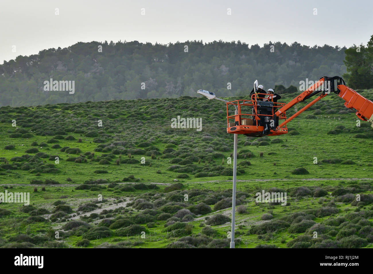 Worker in lift bucket repair street light pole. Modernization of street