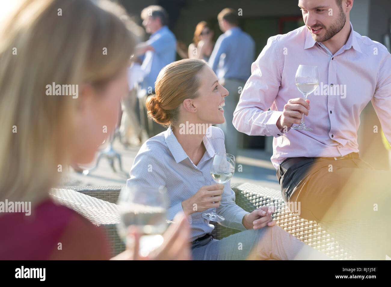 Happy young businesswoman talking with businessman during at rooftop party Stock Photo