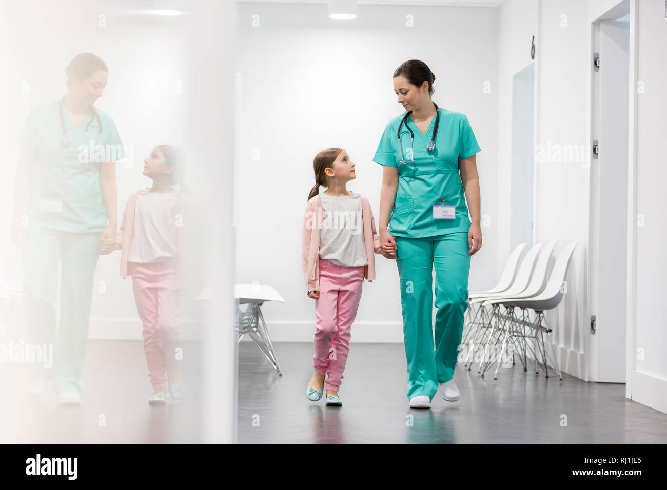 Nurse and girl patient walking in corridor at hospital Stock Photo