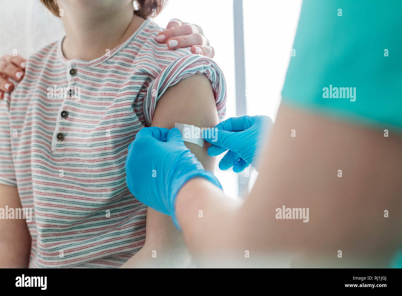 Nurse applying bandage on boy arm at hospital Stock Photo