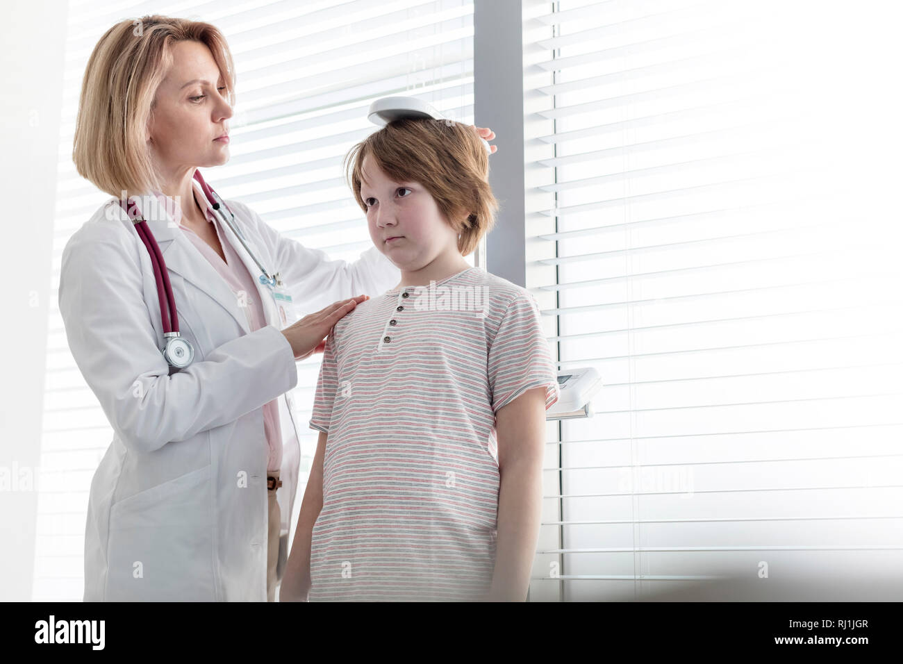 Pediatrician checking height of boy in examination room Stock Photo