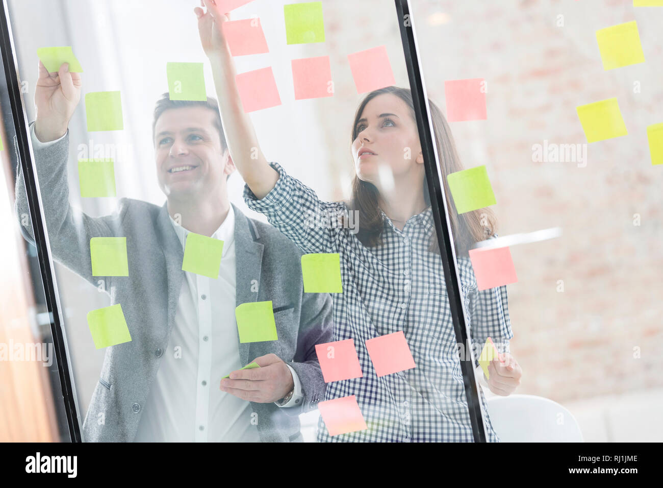 Creative business people sticking notes on glass wall Stock Photo