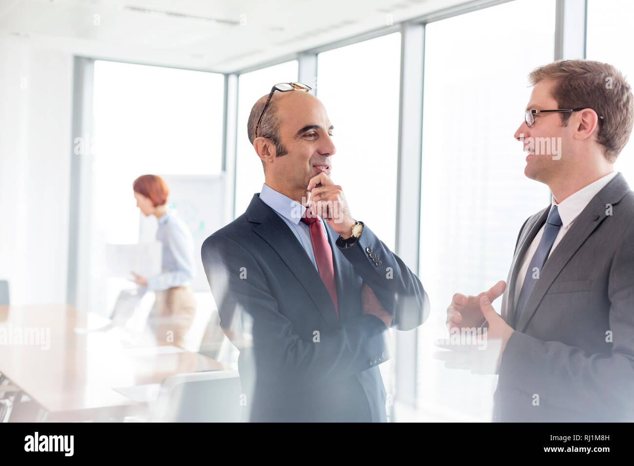 Businessmen discussing while standing in boardroom during meeting at office Stock Photo