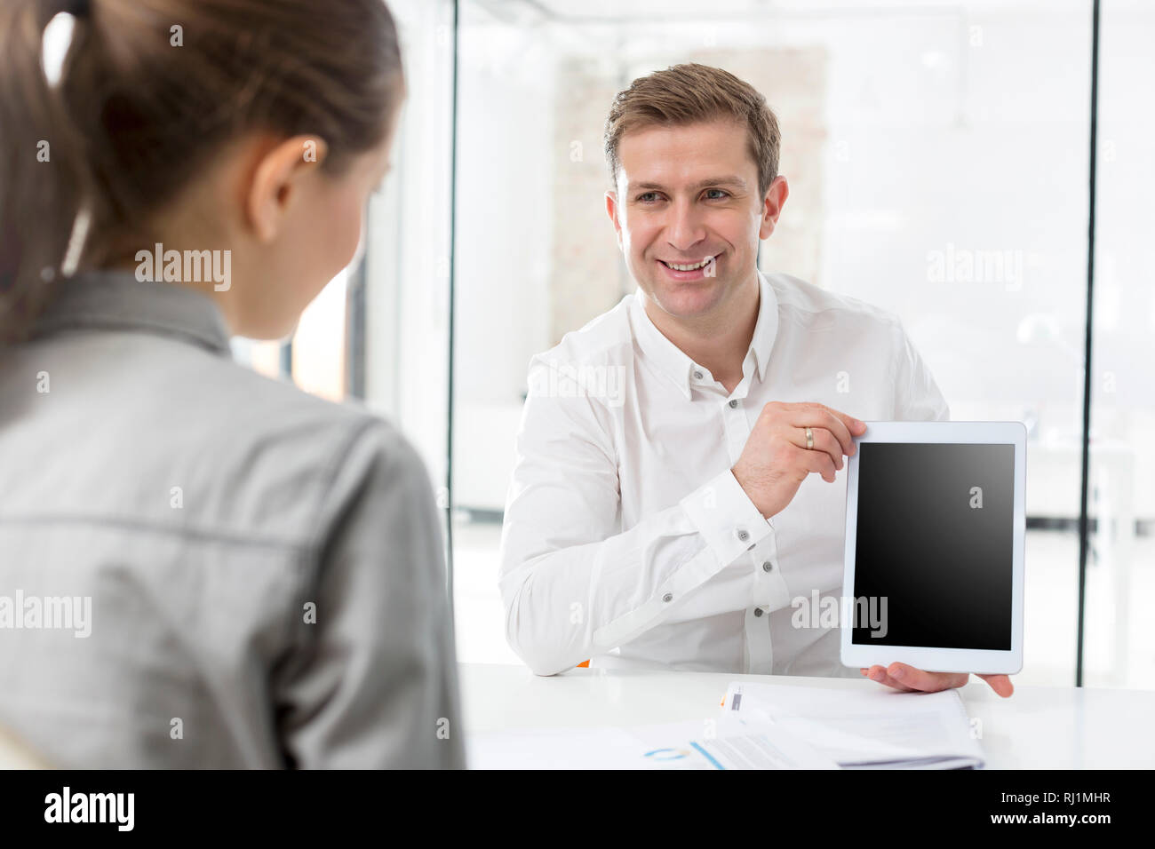 Creative businessman showing digital tablet to colleague in office Stock Photo