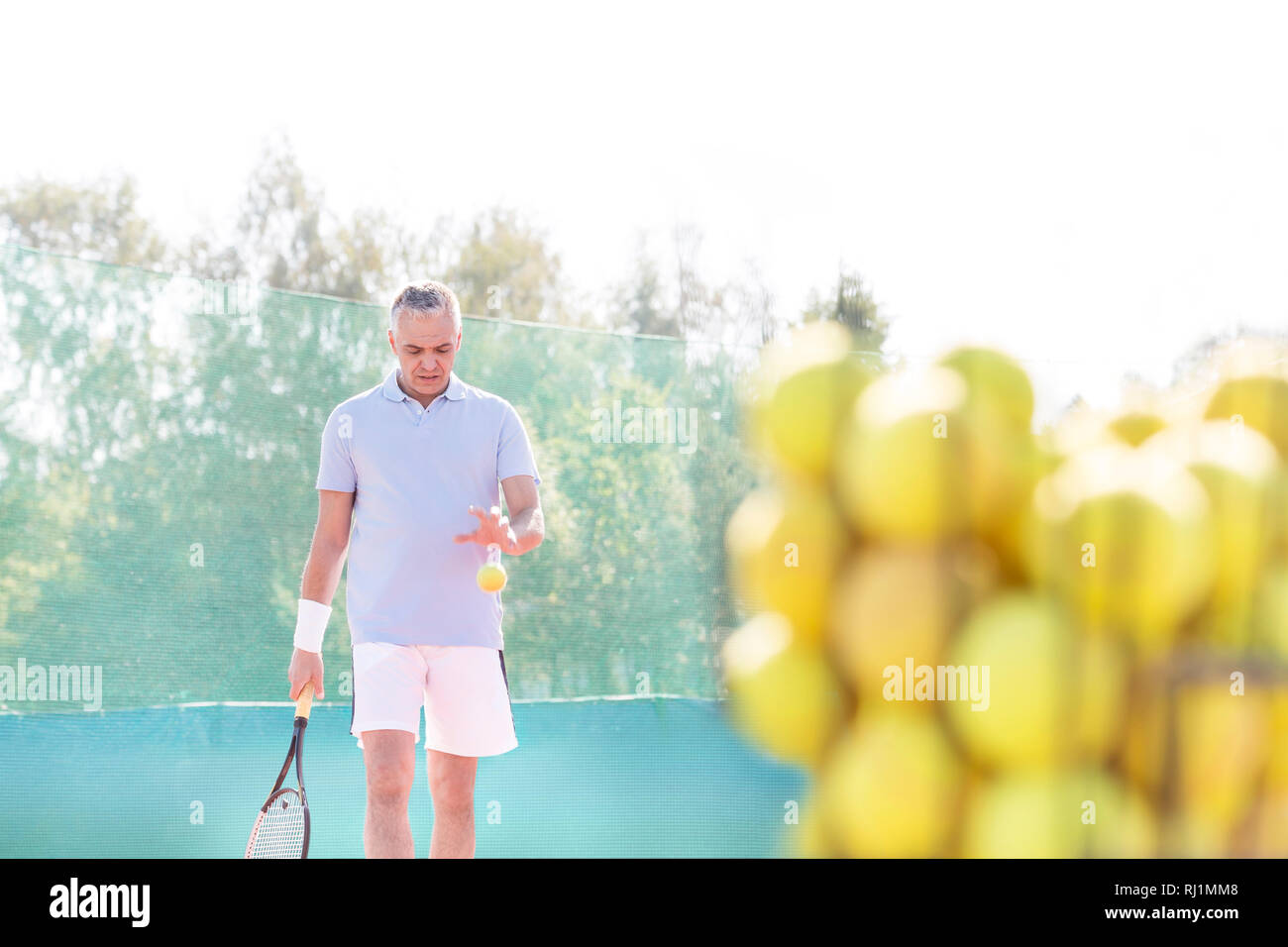 Mature man playing tennis against clear sky on sunny day Stock Photo