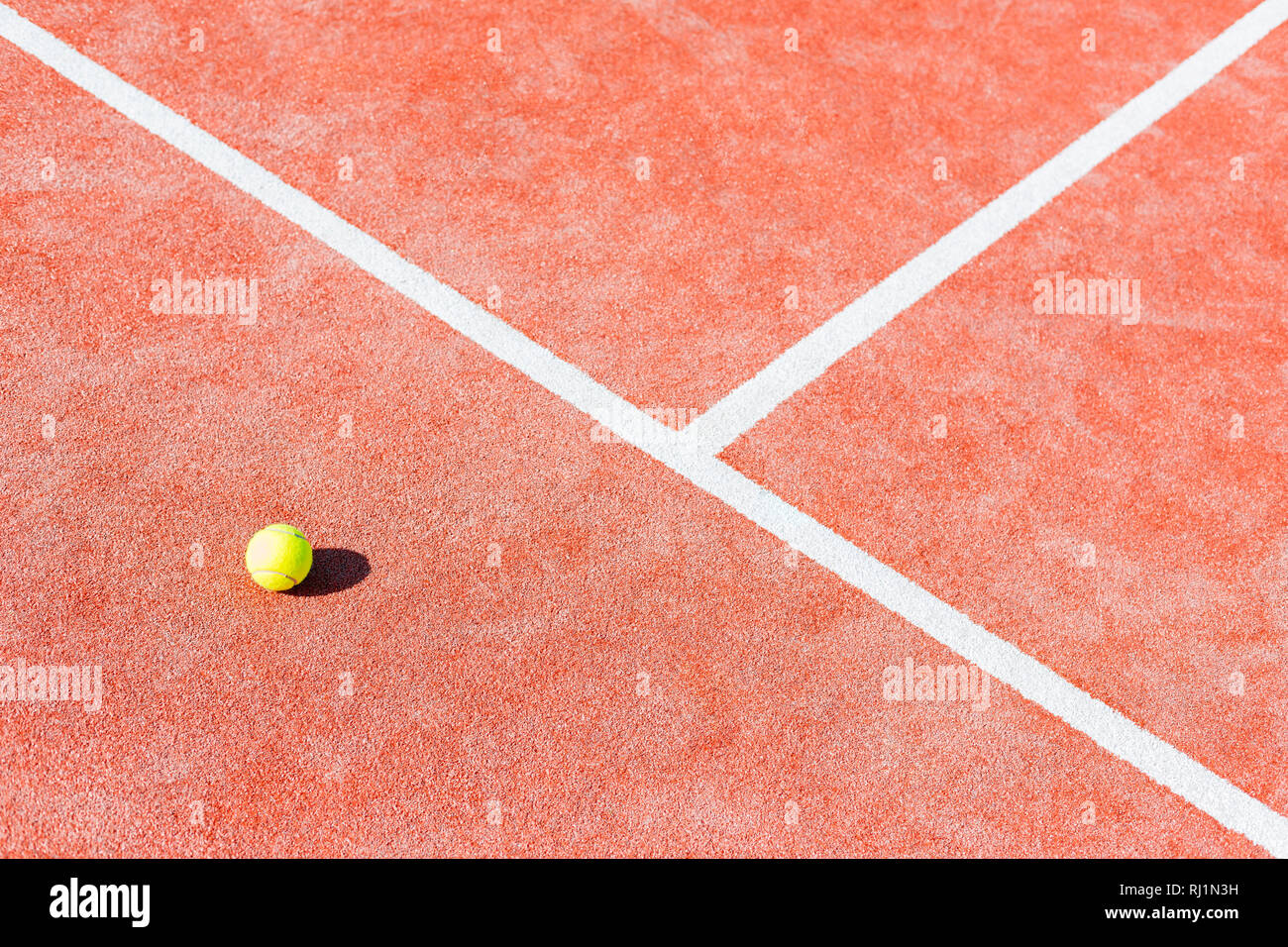 High angle view of tennis ball on red court during sunny day Stock Photo