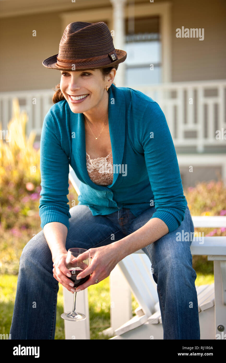 Mature woman enjoys glass of red wine in her backyard Stock Photo - Alamy