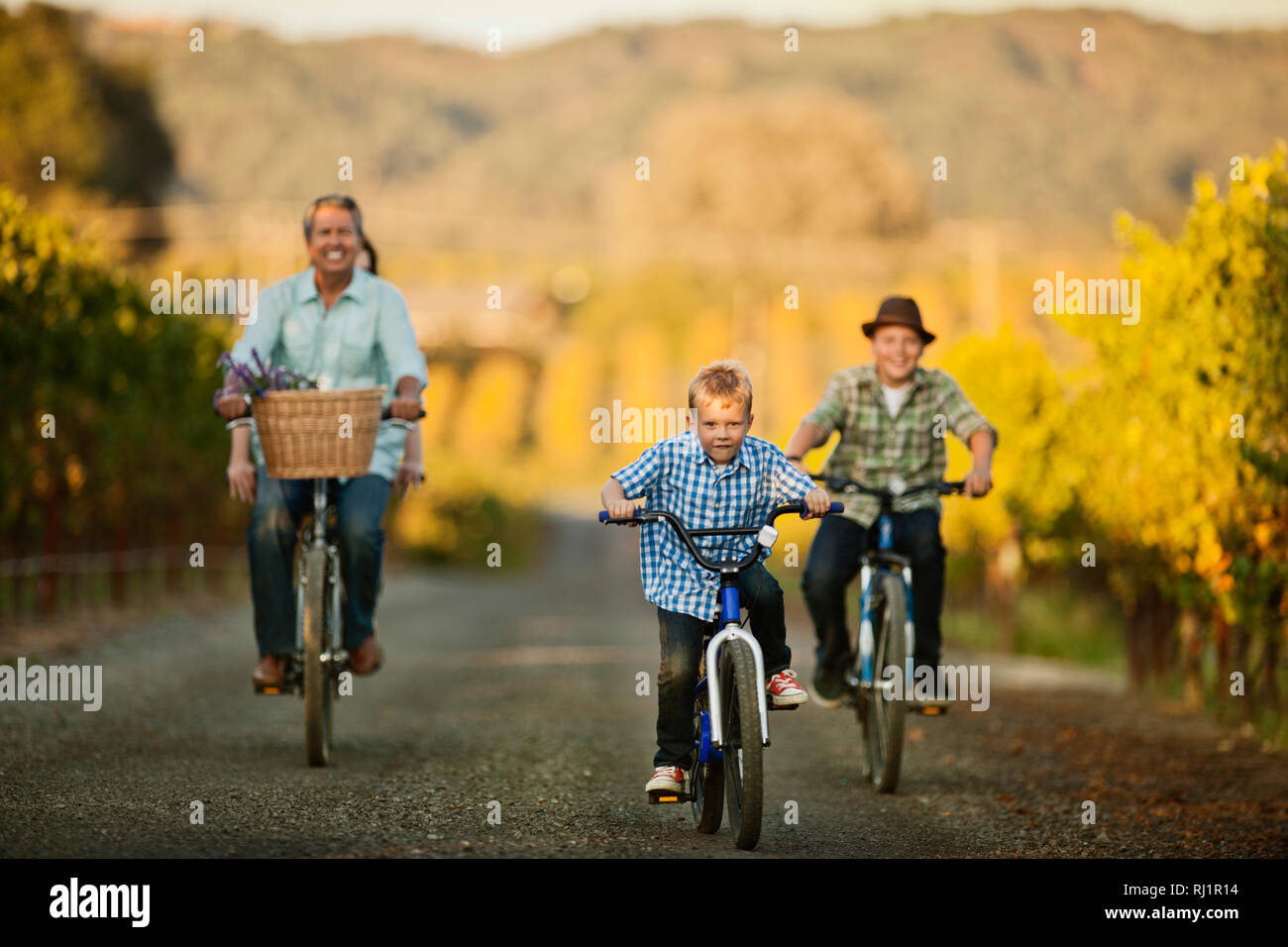 Little boy riding his bicycle with his brother and father. Stock Photo