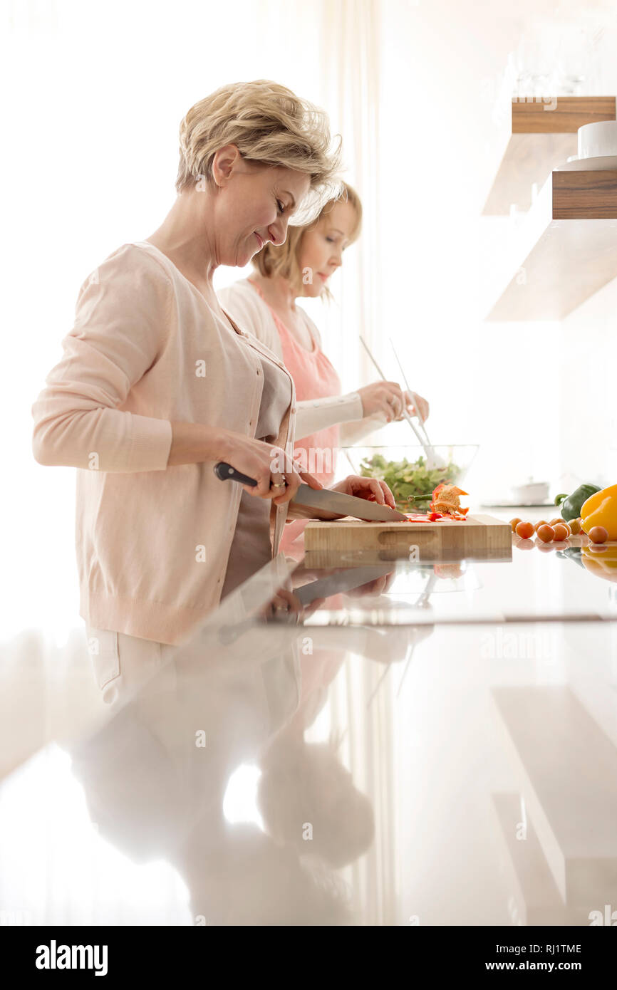 Mature women preparing meal at countertop in kitchen Stock Photo