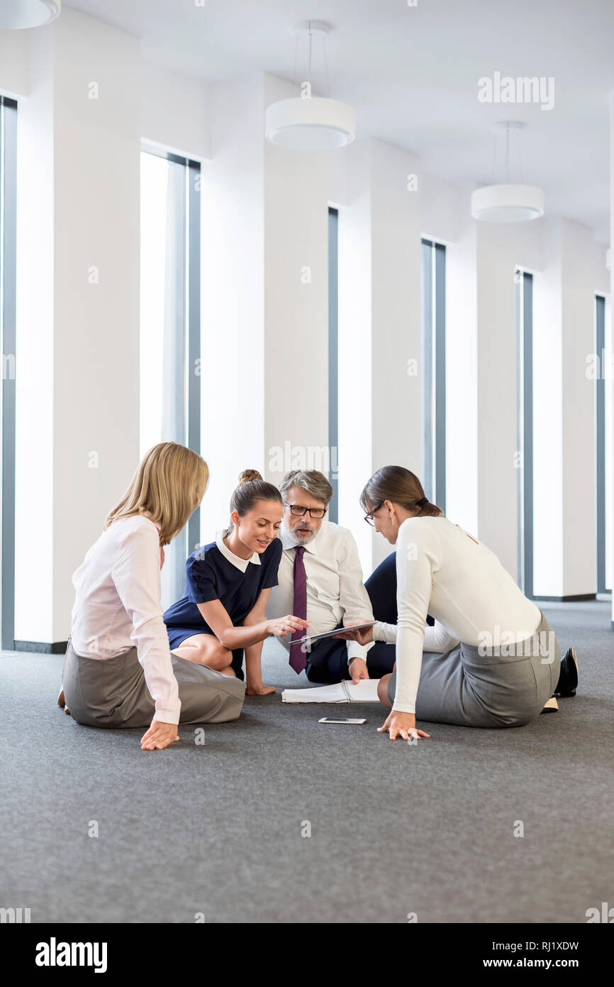 Business people discussing while sitting on floor at office Stock Photo