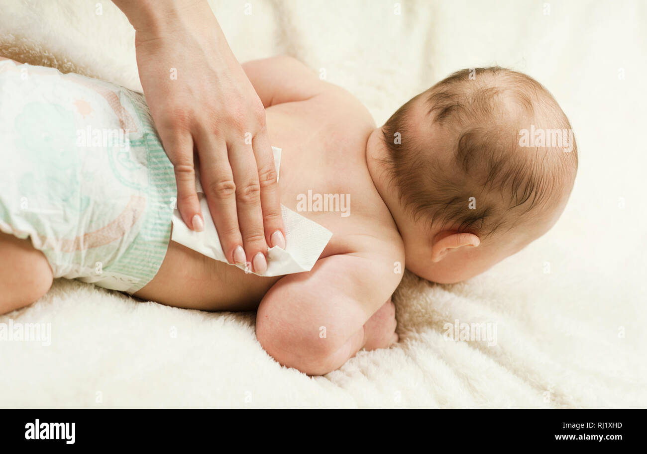 A newborn baby gets a diaper change: the mother wipes the baby with a baby wipe. The concept of cleanliness and care Stock Photo