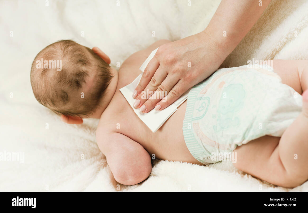 A newborn baby gets a diaper change: the mother wipes the baby with a baby wipe. The concept of cleanliness and care Stock Photo
