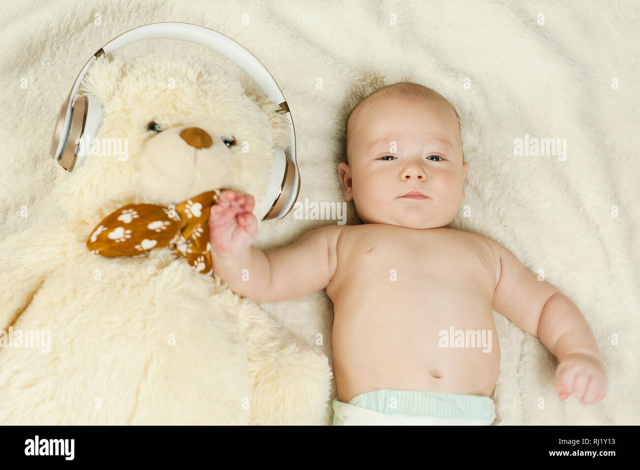 beautiful newborn baby in big headphones listening to music, isolated on blue background Stock Photo