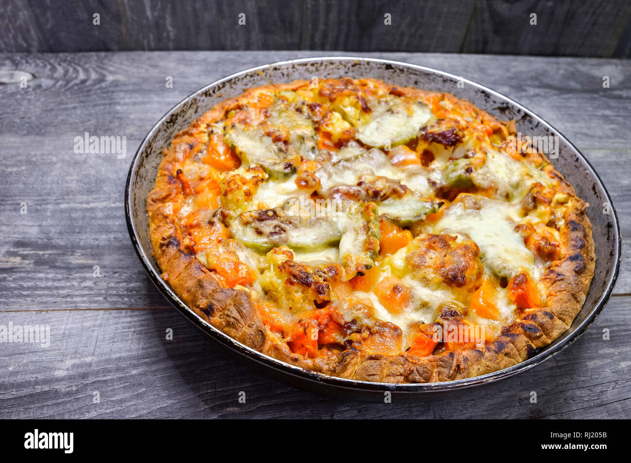 Pie with vegetables and cheese in the pan on a vintage grey wood rustic background Stock Photo