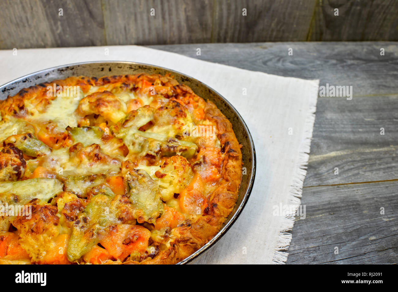 Vegetable and cheese pie in vintage pan on white linen napkin on wooden rustic background Stock Photo