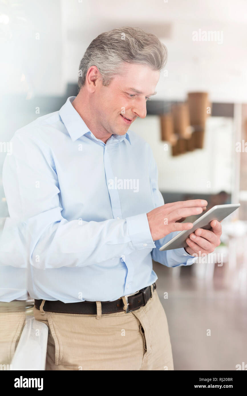 Smiling mature owner using digital tablet while standing by counter at restaurant Stock Photo