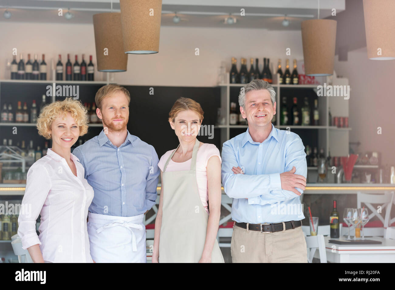 Confident owners and staff standing against counter in restaurant Stock Photo