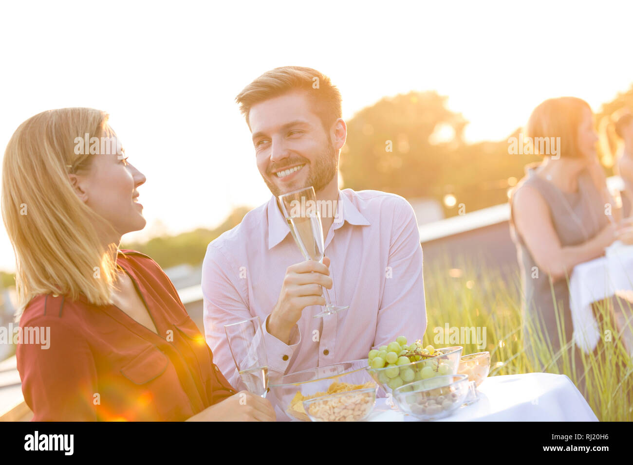 Smiling business colleagues standing at table during rooftop party Stock Photo