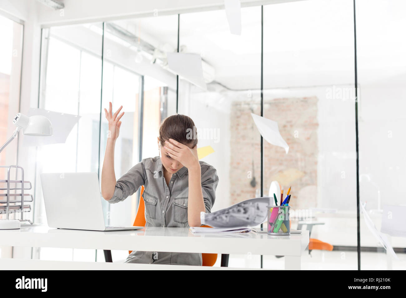 Overworked businesswoman throwing documents at desk in office Stock Photo