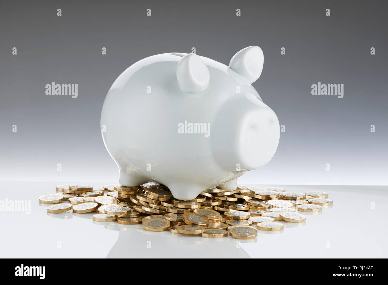 White Contemporary Piggy Bank with Pound Coins Stock Photo
