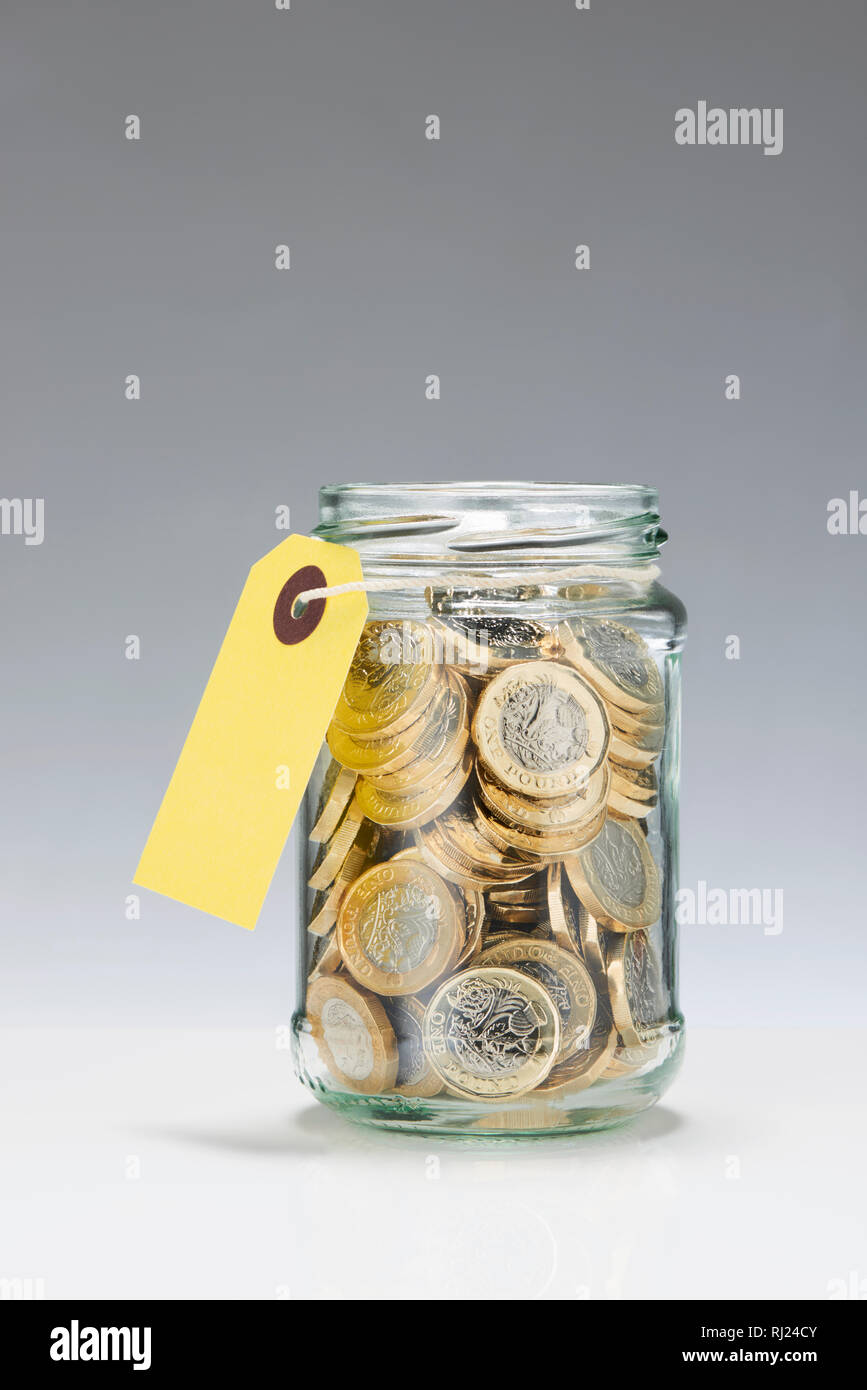 Glass Savings Jar with One Pound Coins Stock Photo