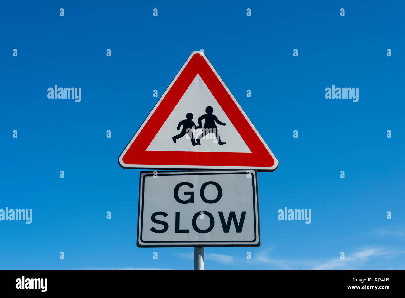 children crossing, go slow warning sign against a blue sky background Stock Photo