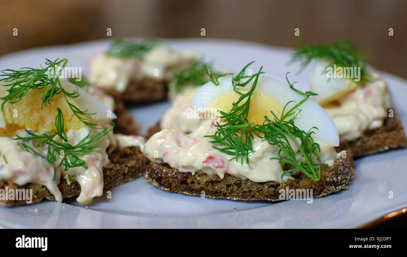 Delicious appetizer: bread topped boiled egg, dill and mousse with  European crayfish. Stock Photo