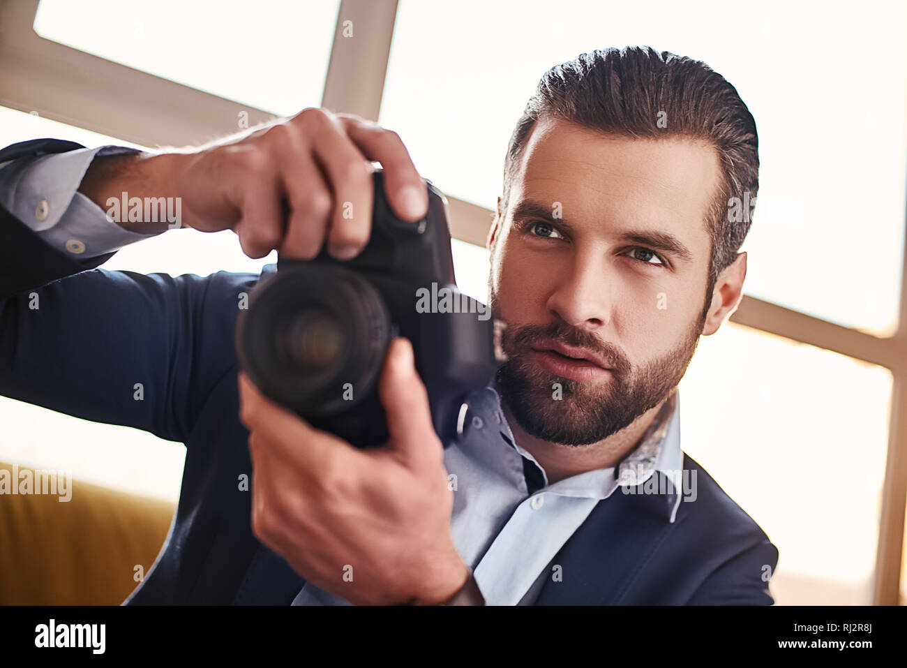 Handsome young businessman in stylish suit is holding camera and going to make a photo. Business look. Close-up Stock Photo
